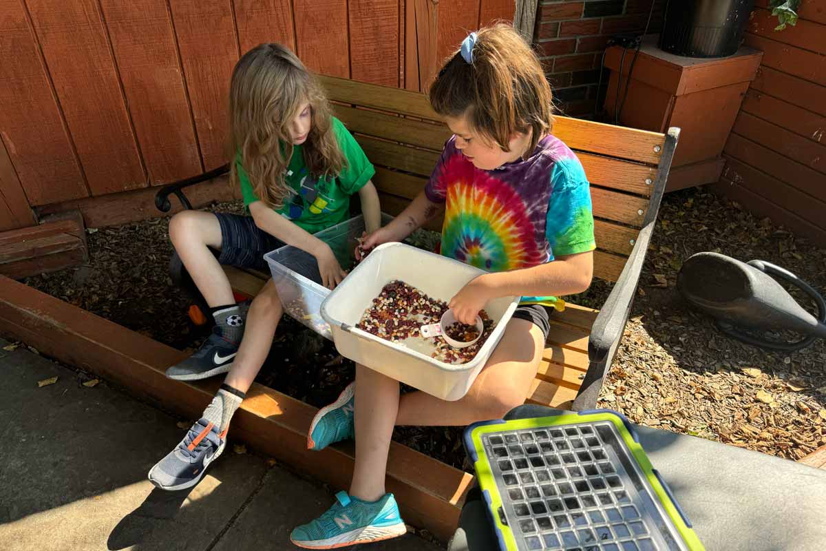 Participants sitting together on a bench doing a sensory activity with dried beans.