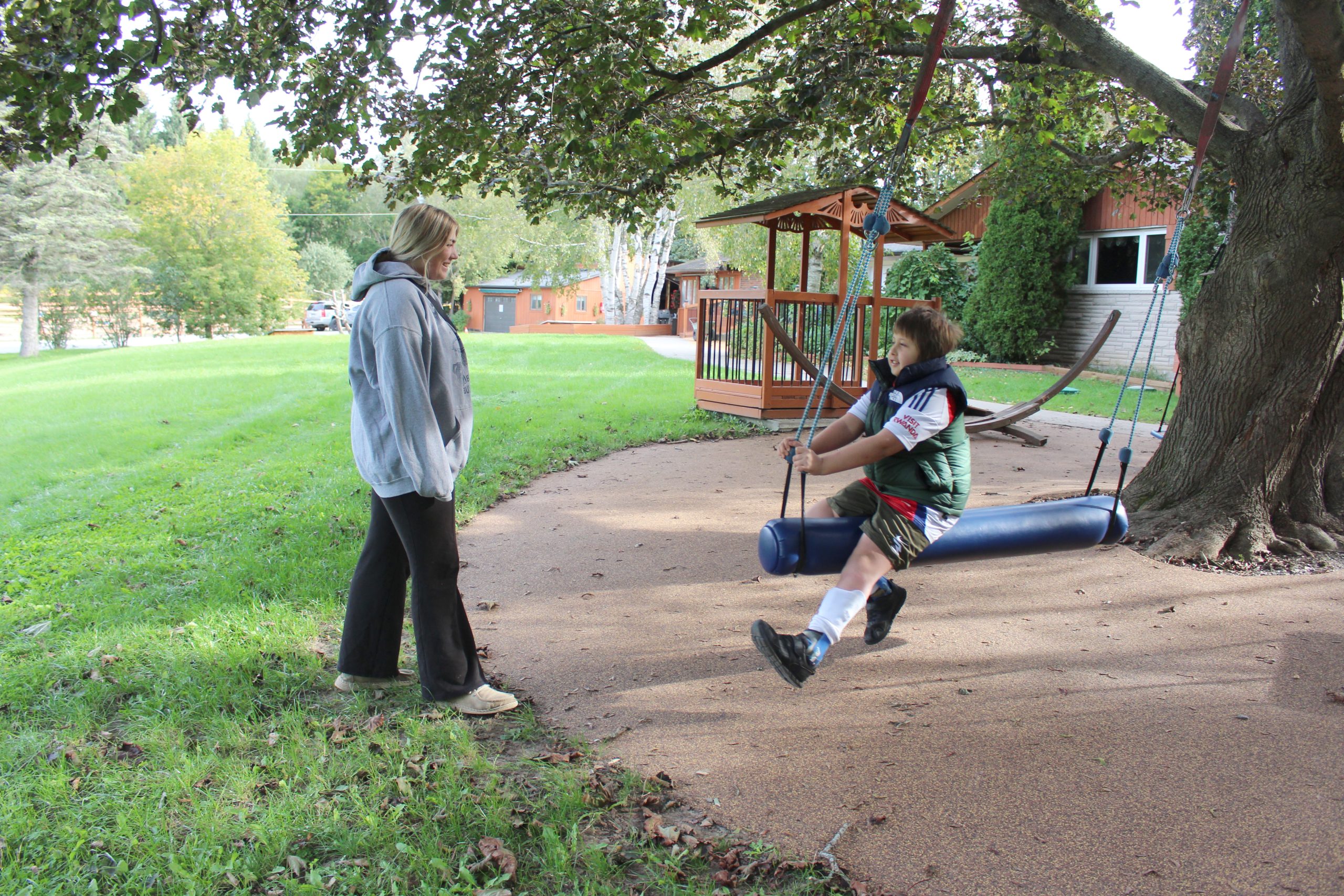 Participant sitting on a cylinder swing smiling at their mentor.
